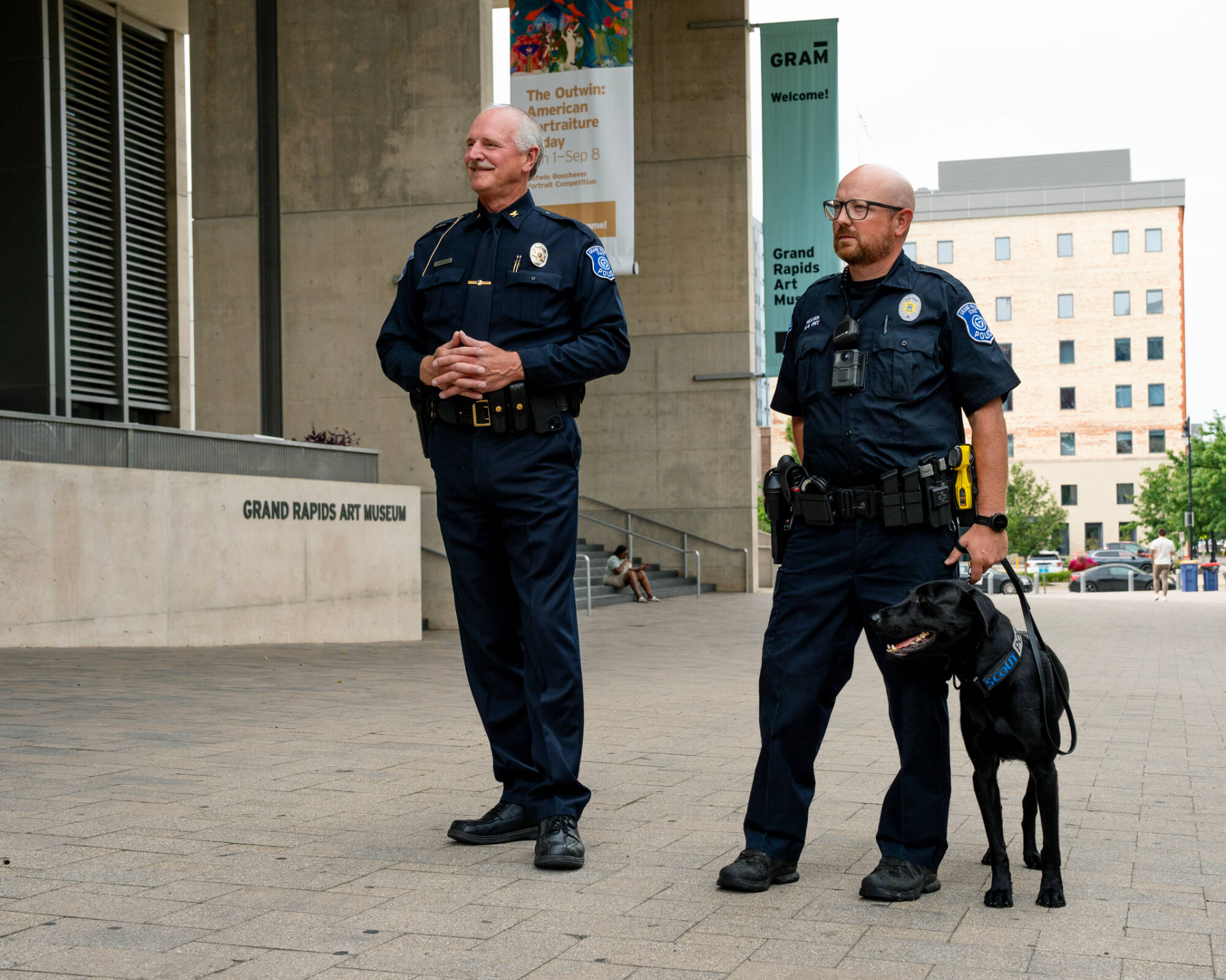 two police officers standing outside, one holding the leash of the service dog